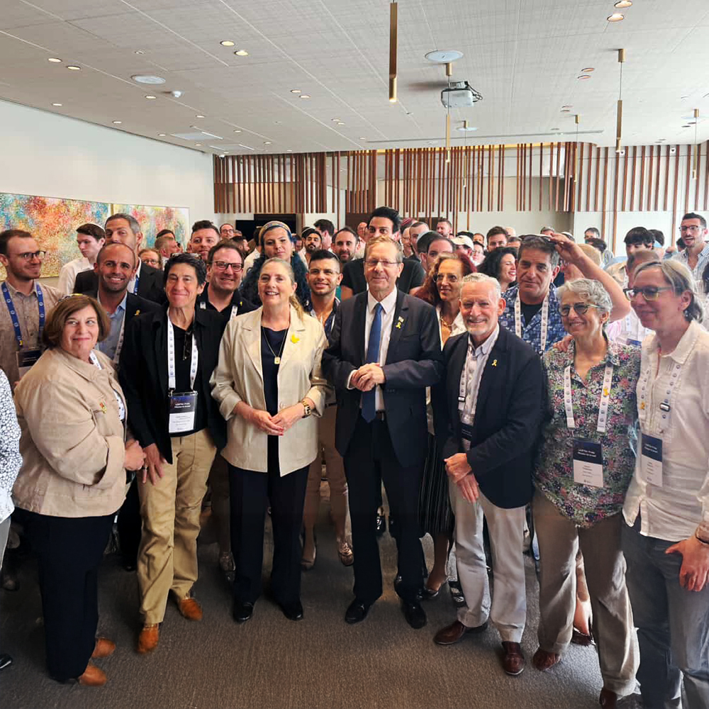 Group of people posing together with the President of Israel in an indoor setting