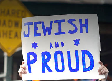 Person holding a sign that reads ‘Jewish and Proud’